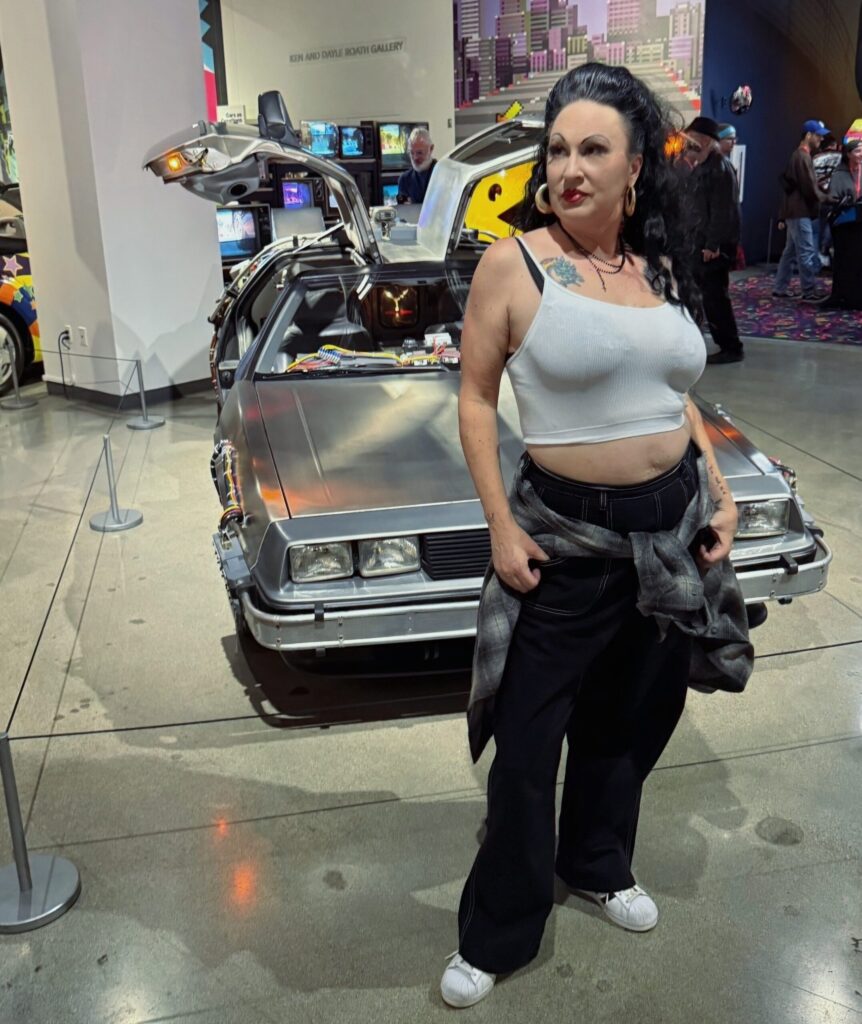 Regina Luz Jordan for Hollywoodland News in front of the 1981 DeLorean DMC-12 Time Machine from Universal Pictures' Back to the Future 1985 at the Petersen Automotive Museum for their Totally Awesome Exhibit on 80s and 90s cars and culture. Photo by Mark Jordan for Hollywoodland News