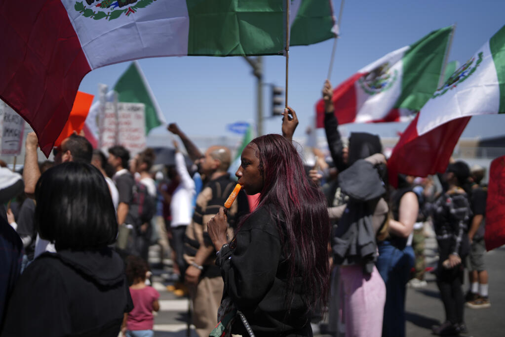 A protester cools down with an icicle while joining other protesters waving Mexican National Flags during a protest to denounce ICE, U.S. Immigration and Customs Enforcement, operations in the area Tuesday, June 10, 2025, in downtown Los Angeles Protests 2025. (AP Photo/Eric Thayer)